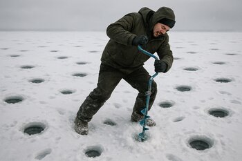 Начинающий рыбак бурит лунки беспорядочно на ровном снежном поле